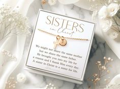 a card with a cross on it sitting next to flowers and a necklace that says, sisters in christ