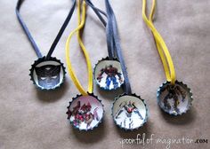 four bottle caps with images of people on them hanging from yellow ribbon and black cord