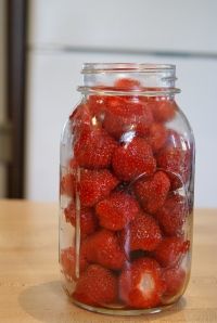 a glass jar filled with strawberries on top of a wooden table