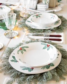 the table is set for christmas dinner with holly decorations