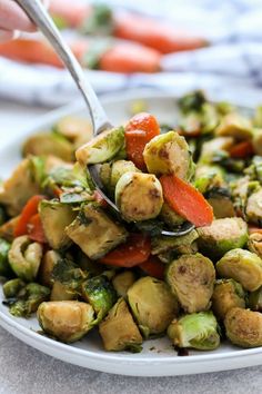 a white plate topped with brussel sprouts and carrots next to a fork