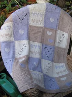 a blanket with hearts on it sitting in a chair next to plants and potted plants