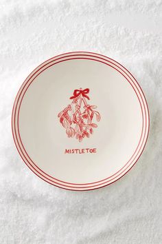 a red and white plate that says mistlet toe on the front with a bow