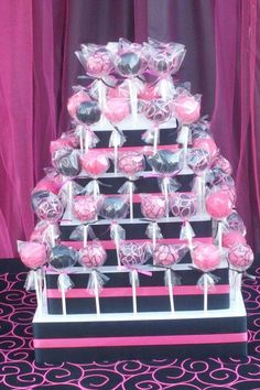 there is a cake made out of lollipops on a stand with pink and black decorations