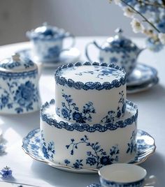 a blue and white cake sitting on top of a table next to teacups