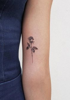 a woman's arm with a single rose tattoo on the left side of her arm