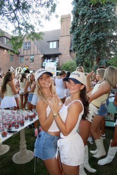 two women standing next to each other in front of a table with cupcakes on it