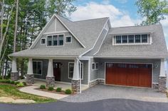 a large gray house with two garages on the front and one story above it