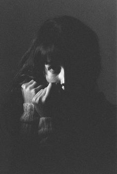 a black and white photo of a woman with her hand on her face in the dark