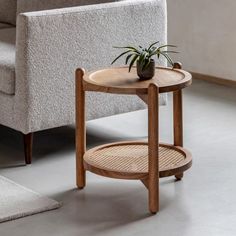 a small table with a potted plant on it in front of a gray couch