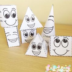 three paper cones with faces on them sitting on top of a wooden table next to each other