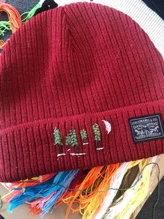 a red hat sitting on top of a table next to yarn and other crafting supplies