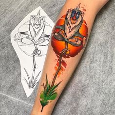 a tattoo on the arm of a person with an orange and green flower in front of them