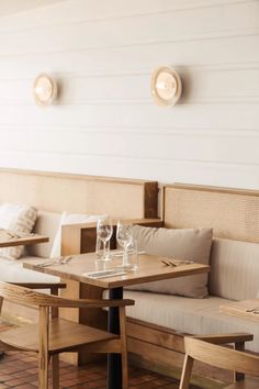 a table with two wine glasses on it in front of some couches and pillows