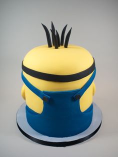 a yellow and blue cake topped with a minion