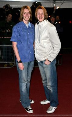 two people standing next to each other on a red carpet