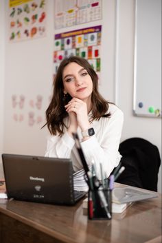 a woman sitting at a desk with a laptop computer in front of her, looking pensive