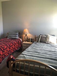 two beds in a room with lamps on either side of the beds and one has a red comforter