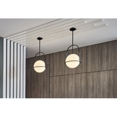 three light fixtures hanging from the ceiling in an office space with wood paneling and white columns