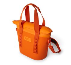 an orange yeti cooler bag on a white background with the handle extended and strap down