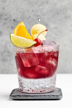 a glass filled with ice and fruit on top of a table