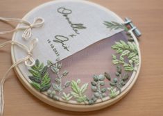 a close up of a embroidery on a piece of cloth with green plants and leaves