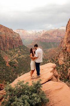 a man and woman standing on top of a cliff