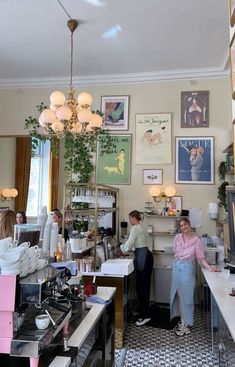 people are standing in a room with many pictures on the wall and tables below them