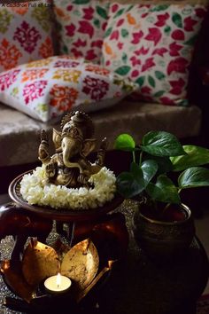 an elephant statue sitting on top of a table next to a potted plant and candle