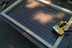 a pair of tools are laying on the ground next to a wire mesh grid fence