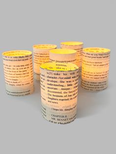 five lit candles sitting next to each other in front of a book page pattern on a gray background