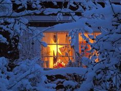 the window is covered in snow and lit up at night, with candles on the windowsill