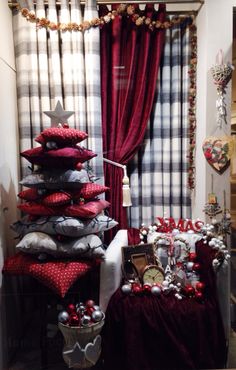 a christmas tree made out of pillows in front of a window with red drapes