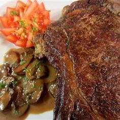 steak with mushrooms and tomatoes on a white plate