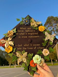 someone holding up a graduation cap decorated with flowers