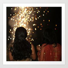 two women looking at fireworks in the sky with heart shaped lights on it's sides