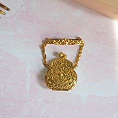 "Vintage 1955 -1959 Lisner Handbag Purse Locket Brooch, Kiss Clasp, Gold Tone, Ornate Raised Design, Chain & Bar, Costume Jewelry, Women This unique locket-style brooch from Lisner Jewelry, was made between 1955 and 1959, based on the mark, which was only used between those year.  It's in very good condition, and all pieces function as they were intended, too.  Please see all photos, as they are considered part of the description.  Purse Width 1 3/4\"  Total Length 2.5\"" Vintage Medallion Brooches For Wedding, Vintage Medallion Brooch For Wedding, Antique Gold Brooches From Vintage Collection, Antique Gold Brooches For Vintage Collection, Gold Antique Brooches For Vintage Collection, Heirloom Gold Brooches For Evening, Heirloom Gold Evening Brooches, Victorian Gold Brooches For Evening, Ornate Gold Brooches For Vintage Events