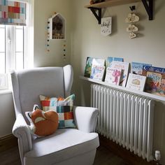 a white chair sitting next to a radiator in a room filled with books