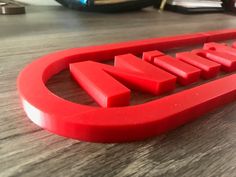 a red metal name plate sitting on top of a wooden table