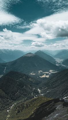 the mountains are covered in green grass and trees, under a cloudy blue sky with white clouds