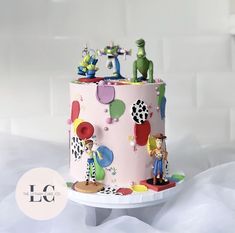 a pink cake decorated with figurines and decorations on top of a white plate