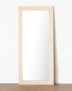 a mirror sitting on top of a wooden floor next to a white wall and wood floor