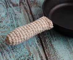 a crocheted object sitting on top of a black pan next to a frying pan