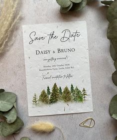 the save the date card is surrounded by greenery