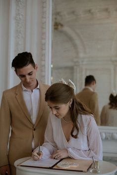 a man and woman sitting at a table writing