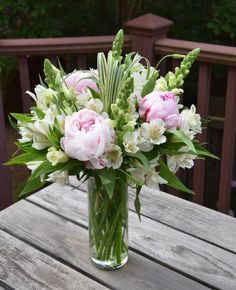 a vase filled with pink and white flowers on top of a wooden table