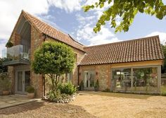 a brick house with an open patio and large glass doors on the front, surrounded by greenery