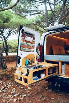 an open camper van parked in the woods