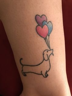 a small tattoo with a dachshund holding balloons in the shape of hearts