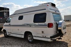 an rv parked on gravel with the door open